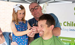 Andrew Cruse gets his head shaved by his daughter